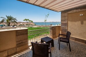 A balcony with a view of the sea, two wicker chairs, a small table, and a tiled floor. - Retac Abu Simbel (Abu Simbel)