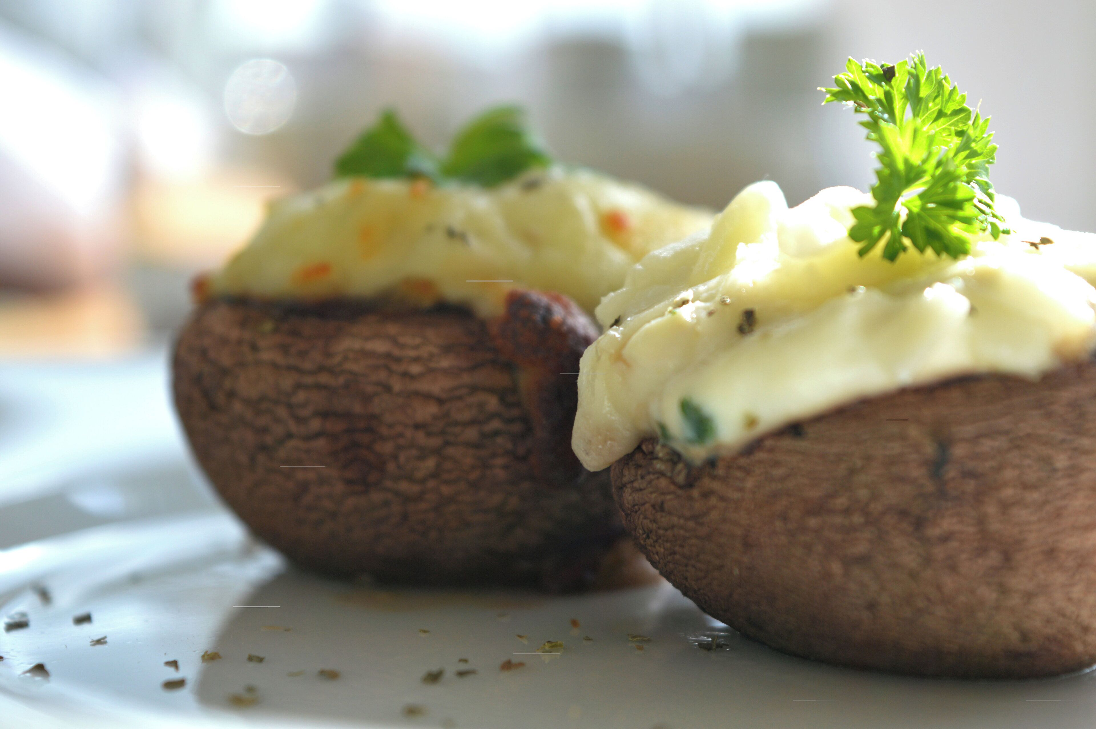 Zwei gebackene Kartoffeln mit cremiger Soße und Petersilie garniert.
