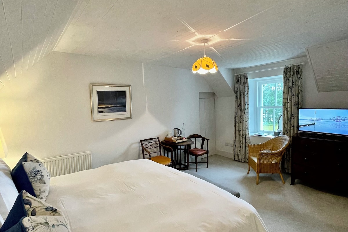 Ein Schlafzimmer mit einem großen Bett, einem Schreibtisch, einem Stuhl und einem Fernseher.