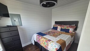 A bedroom with two beds, a dresser, and a ceiling fan. - Tiny Home with Rooftop Deck (Pikeville)