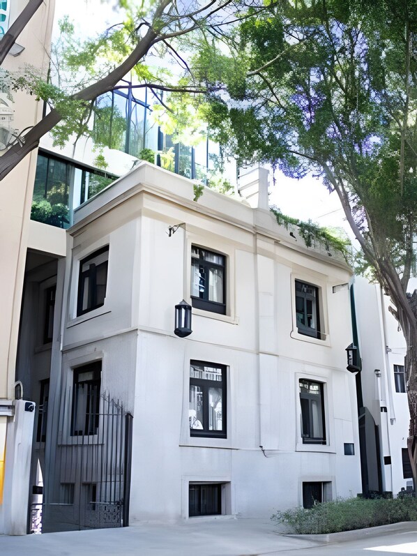 A multi-story building with a white facade, large windows, and a gated entrance.