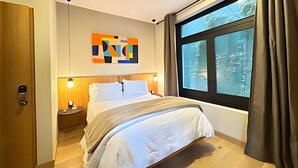 A modern hotel room with a large bed, a nightstand, a wall art piece, and a window with curtains. - Modern Suite 3 - Heart of Roma Norte (Mexico City)