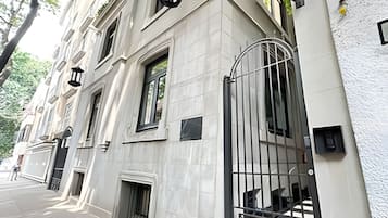 Un edificio con un gran portón de entrada, varias ventanas y una acera pavimentada.