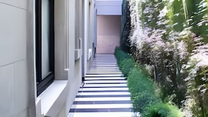 A narrow, tiled pathway flanked by buildings and greenery, leading to a door at the end. - Modern Suite 3 - Heart of Roma Norte (Mexico City)