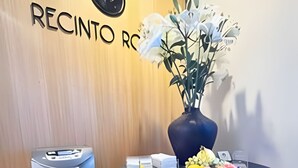 A reception desk with a vase of flowers, a water dispenser, and a small table with a bowl of fruit. - Modern Suite 3 - Heart of Roma Norte (Mexico City)
