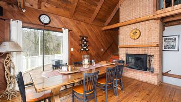 A wooden dining area with a brick fireplace, a clock, and a wine rack.
