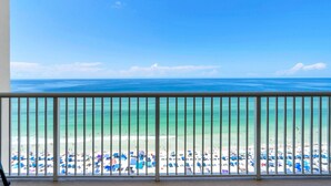 A balcony with a view of a beach with umbrellas and people. - New Majestic BeachFront -Indoor pool, Starbucks (Panama City Beach)