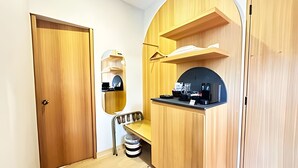 Ein schlichter Raum mit Holztür, einer kleinen Sitzbank, einem Spiegel und einem Tischchen mit diversen Gegenständen.