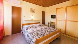 A bedroom with a wooden bed, a desk with a chair, a television, and a wardrobe.