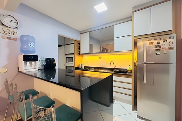 A modern kitchen with a central island, a built-in oven, and a refrigerator.