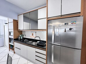 Une cuisine moderne dotée d’appareils électroménagers en acier inoxydable, de meubles en bois et d’un plan de travail noir.