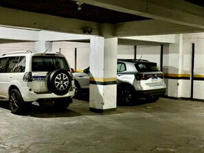 A parking garage with two white SUVs parked in adjacent spaces.