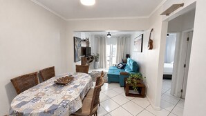 A dining area with a table set for four, a sofa, and a small side table with a plant. - Republica Argentina (Balneário Camboriú)