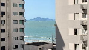 A high-rise building with multiple balconies overlooking a calm sea and distant mountains. - Republica Argentina (Balneário Camboriú)