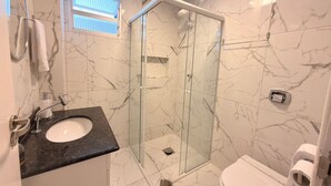 A bathroom with a glass-enclosed shower, a sink with a marble countertop, and a toilet. - Republica Argentina (Balneário Camboriú)