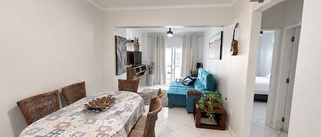 A dining area with a table set for four, a sofa, and a small side table with a plant.