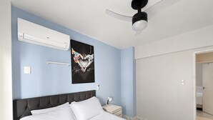 A hotel room with a bed, a nightstand, a wall-mounted air conditioner, a ceiling fan, and a poster on the wall. - Republica Argentina (Balneário Camboriú)