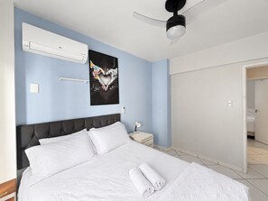 A hotel room with a bed, a nightstand, a wall-mounted air conditioner, a ceiling fan, and a poster on the wall. - Republica Argentina (Balneário Camboriú)