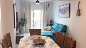 A dining area with a round table, wicker chairs, a blue sofa, and a potted plant.