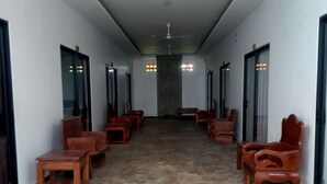 A hallway with a ceiling fan, wooden chairs, and tables arranged along the walls. - Siem Reap Local Stay (Siem Reap)