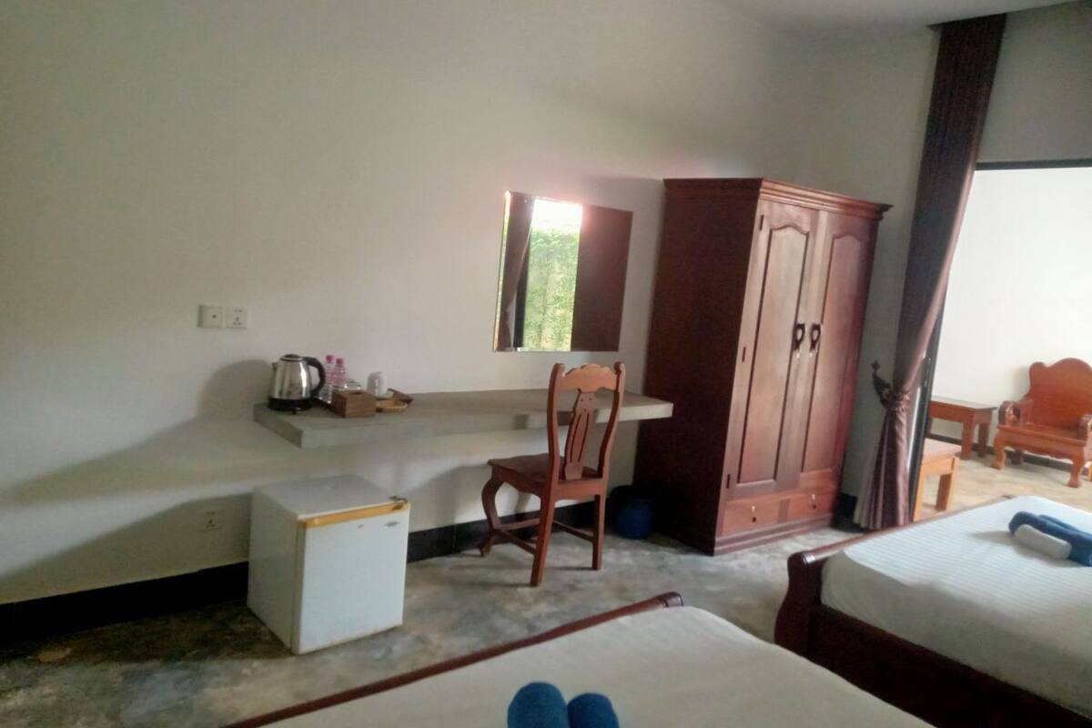 A hotel room with a bed, a desk, a chair, a wardrobe, and a small table.