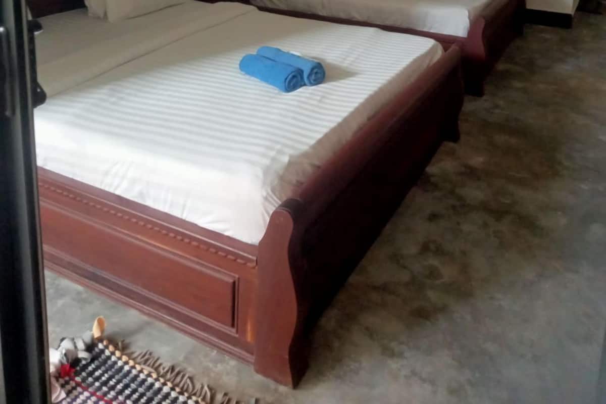 A hotel room with two wooden beds, white bedding, and a blue towel on one bed.