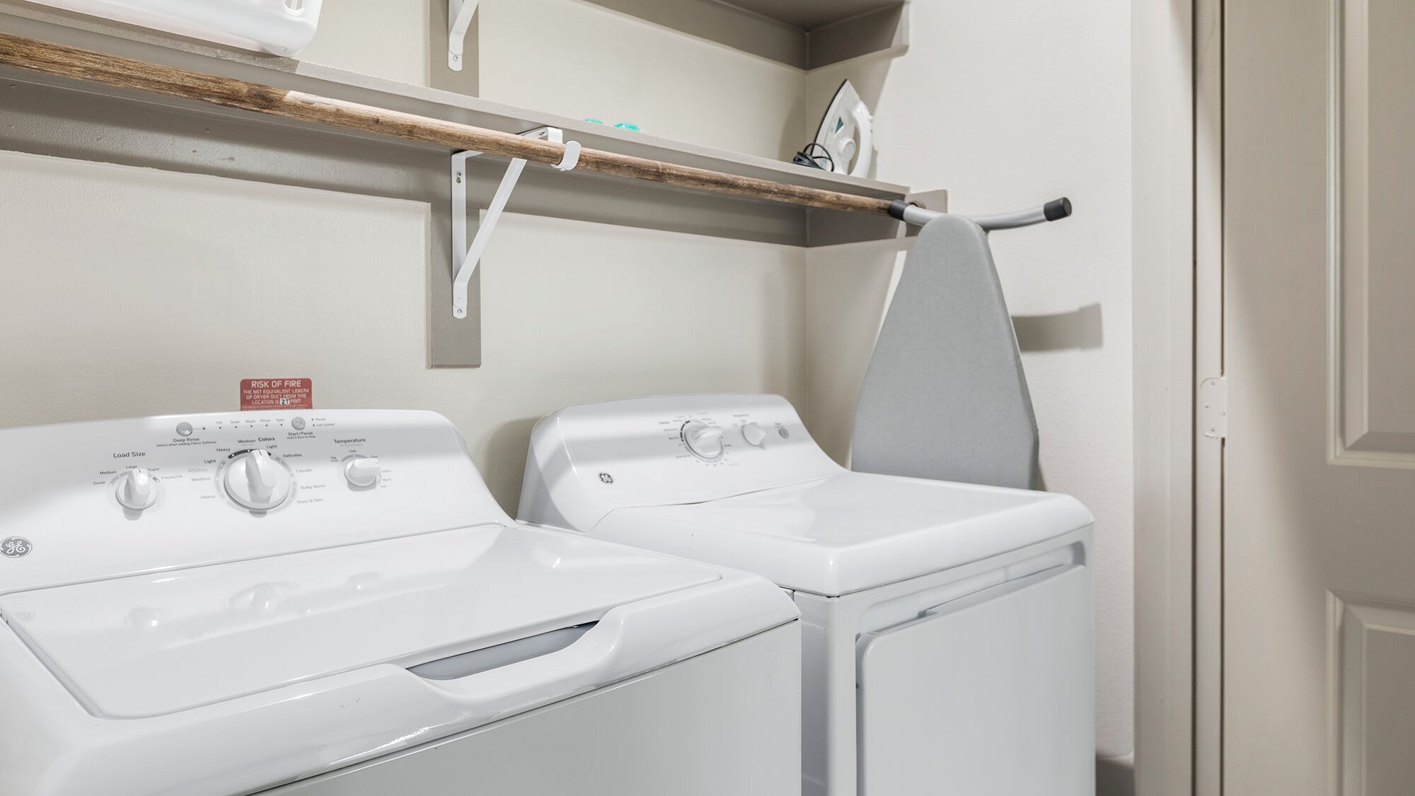 A laundry area with two front-loading washing machines and a drying rack.