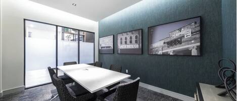 A conference room with a white table, black chairs, and a glass partition.