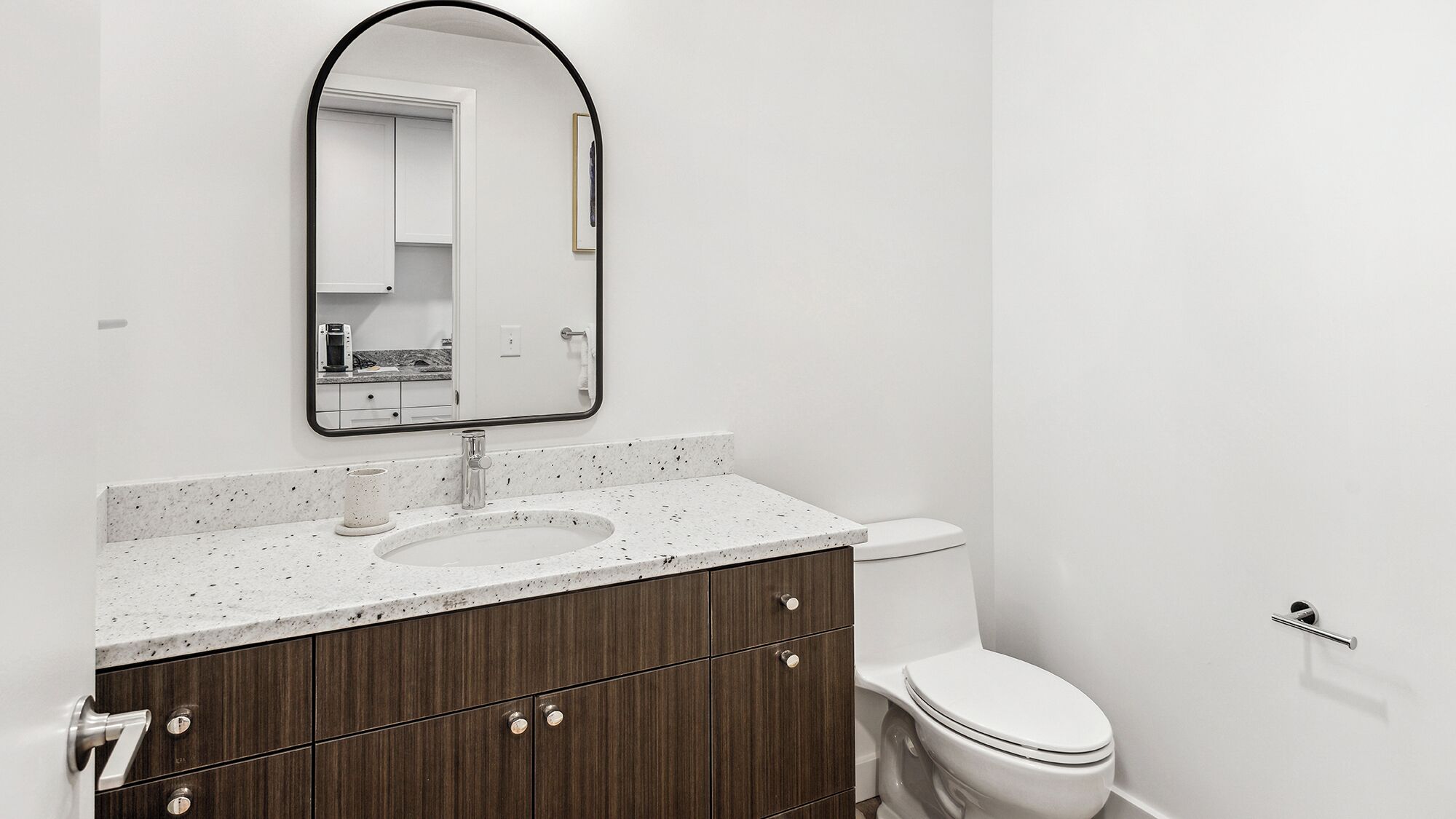 A modern bathroom with a white sink, dark wood vanity, and a white toilet.