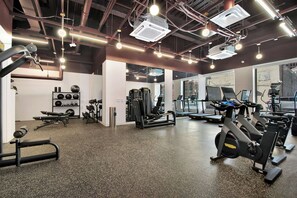 Et moderne fitnesscenter med forskellig træningsudstyr, herunder løbebånd, styrkemaskiner og håndvægte.