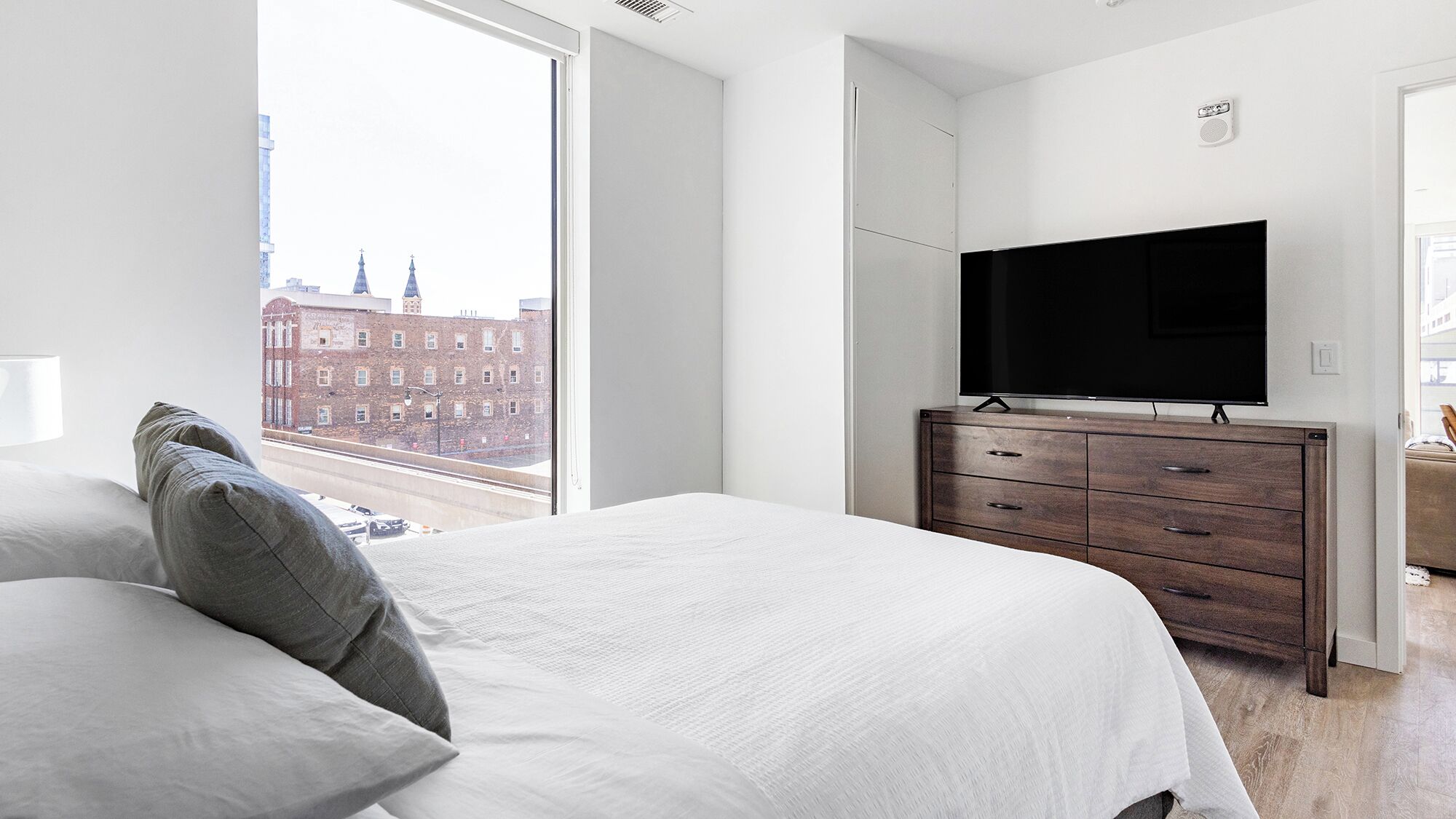 A modern bedroom with a large bed, a dresser, and a flat-screen TV.