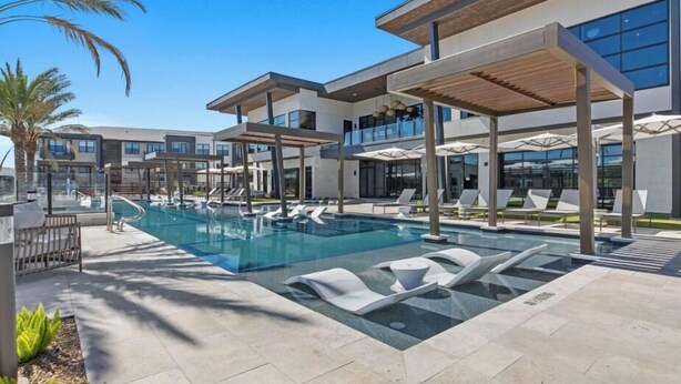 A modern hotel with a swimming pool, sun loungers, and a covered patio area. - Landing Apartments near UT San Antonio (San Antonio)