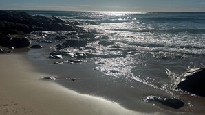 A beach with sunlight reflecting off the water and rocks. - Absolute Beachfront, Panoramic Ocean Views & Whale Season Magic (May–August) 🐳 (Coolum Beach)