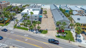 Ein Küstenhotel mit mehreren Gebäuden, einem Strand und einem Parkplatz.