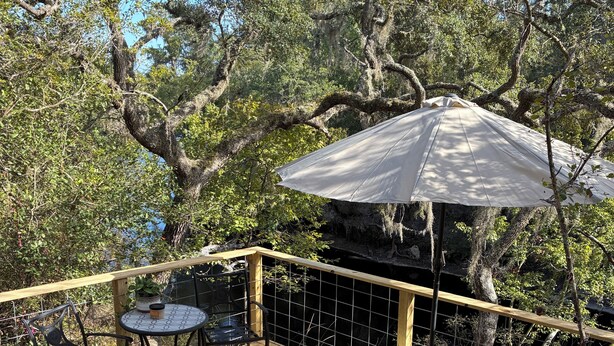 A wooden deck with a table and chairs, a bench, and an umbrella.