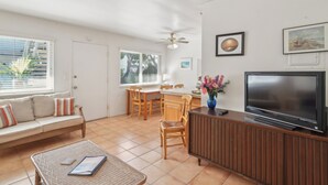 Een woonkamer met een bank, televisie, eettafel en stoelen.