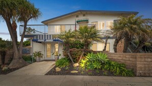 Een gebouw met twee verdiepingen, een balkon, palmbomen en een bord met 'Sunset Shores'.
