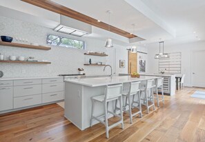 Una cocina moderna con una isla central, taburetes de bar y vigas de madera en el techo.