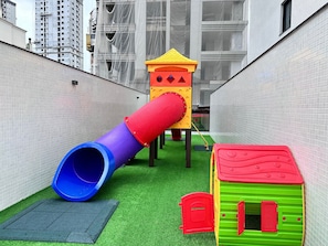 A children's play area with a slide, a climbing structure, and a small house. - Manhattan Flats (Itapema)