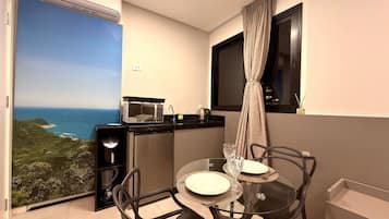 A compact balcony with a view of the sea, a small kitchenette, and a dining area with two chairs and a table.