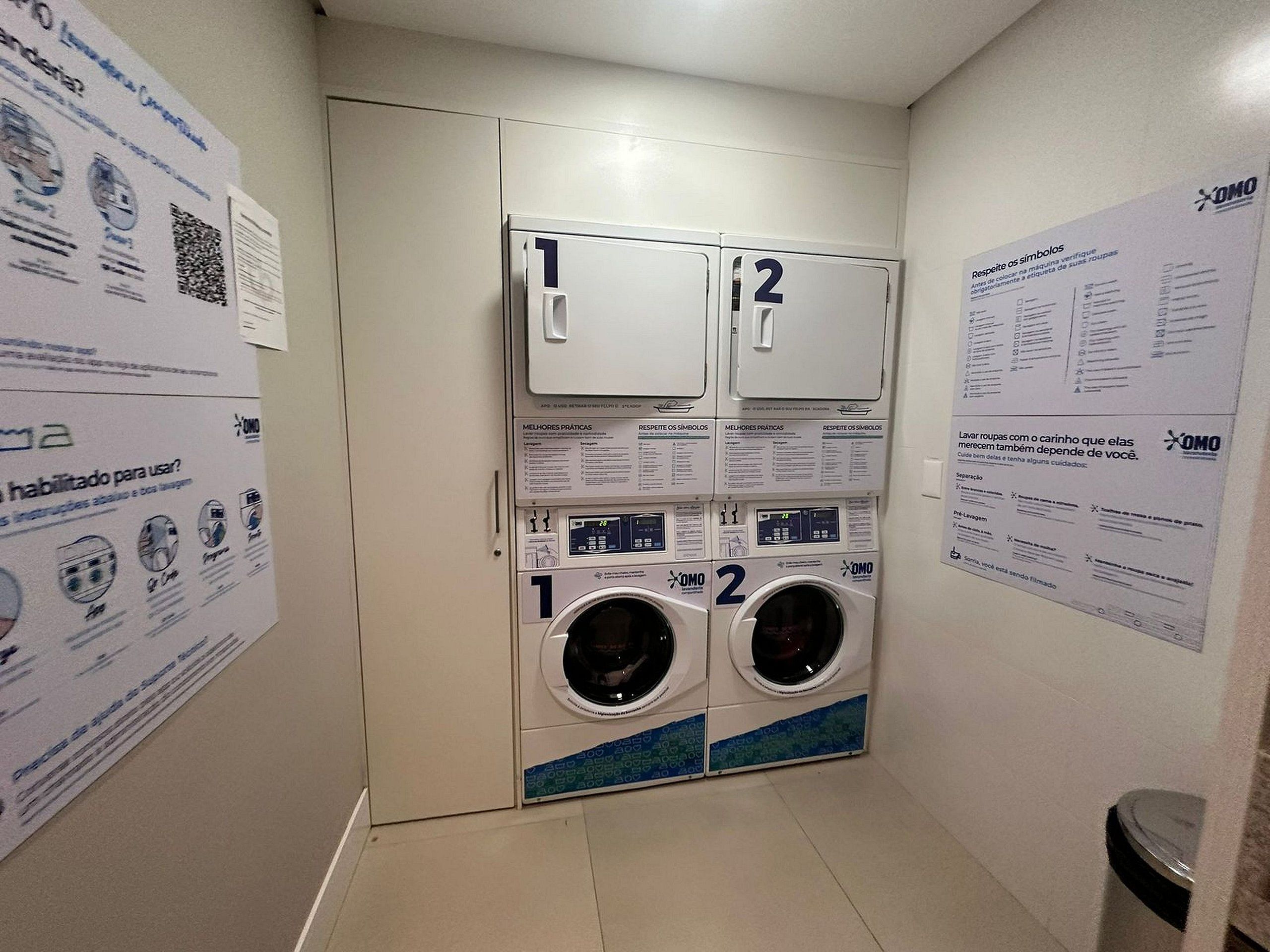 A laundry facility with two washing machines, numbered 1 and 2, and instructional posters on the walls.