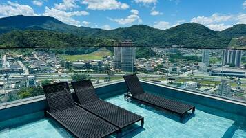 Ein Rooftop-Pool mit Liegestühlen und Blick auf die Stadtlandschaft.