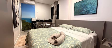 Un dormitorio con cama, escritorio y vista al océano.