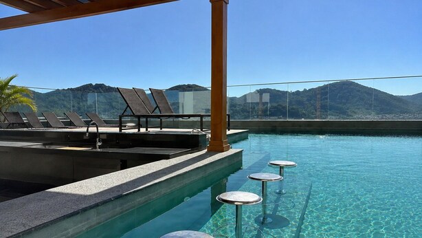 Un área de piscina con sillones reclinables y un bar.
