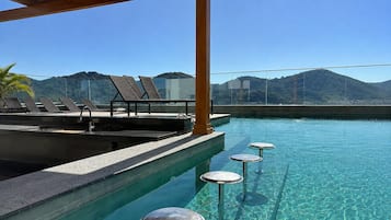 A pool area with lounge chairs and a bar.