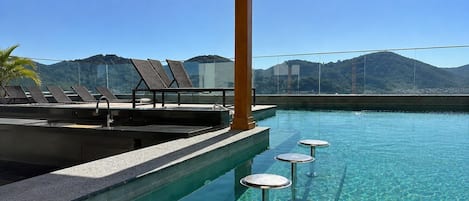 Un área de piscina con sillones reclinables y un bar.