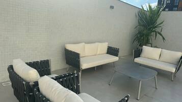 A patio area with outdoor furniture including two sofas and two armchairs, a small table, and a potted plant.