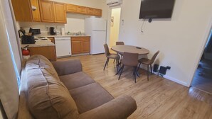 Een gezellig compact verblijf met een bank, eettafel, stoelen, kitchenette en een flatscreen televisie.