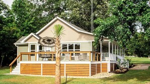 A two-story house with a balcony, a staircase, and a palm tree in the front yard. - Sunset Oasis|PrivateDock|Sleeps8 (Chappells)