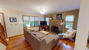 A living room with a fireplace, a sofa, a television, and a bookshelf. - Brookside Cottage In Hocking Hills (Rockbridge)